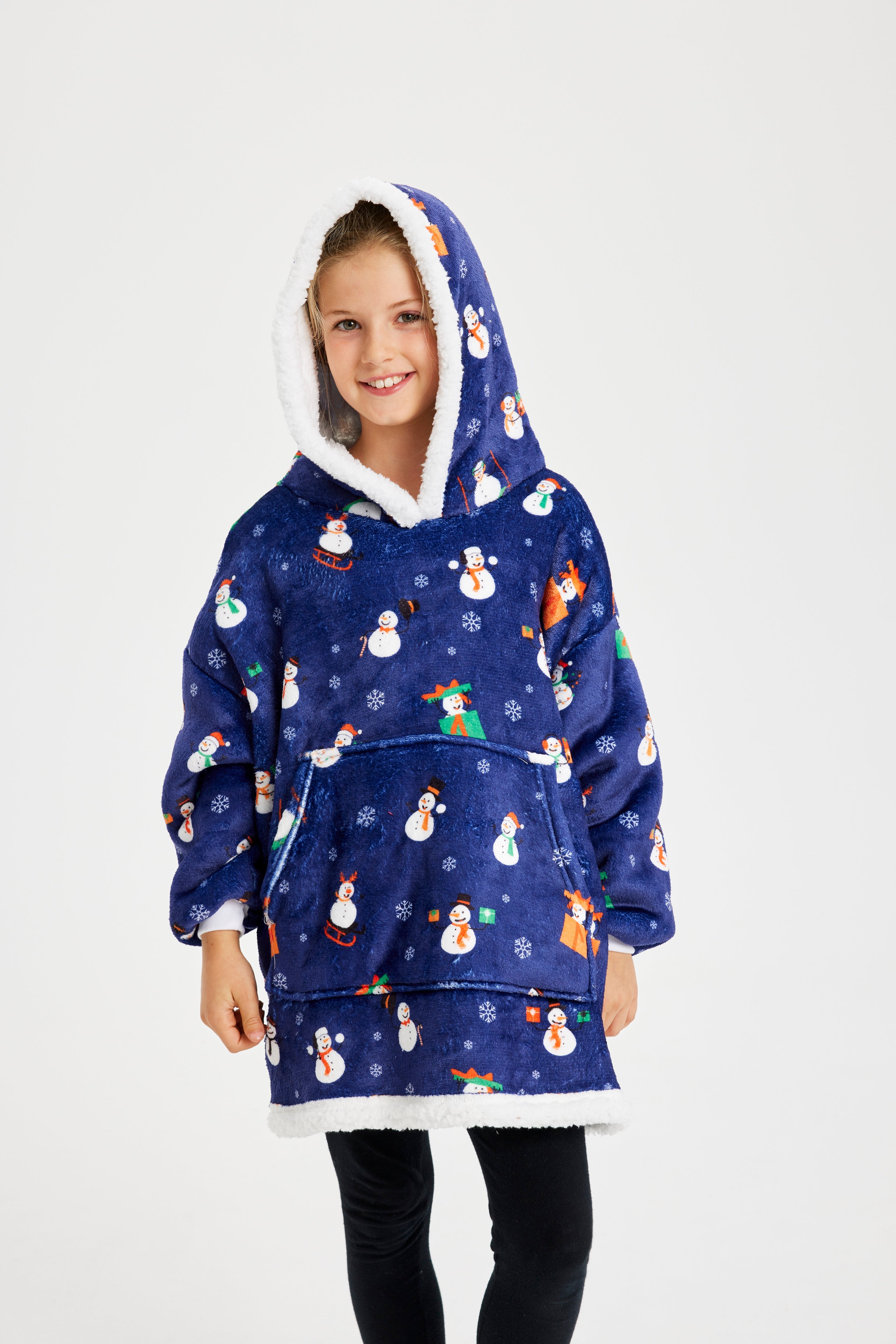 Un enfant qui pose, portant un sweat à capuche bleu avec un motif de Noël.